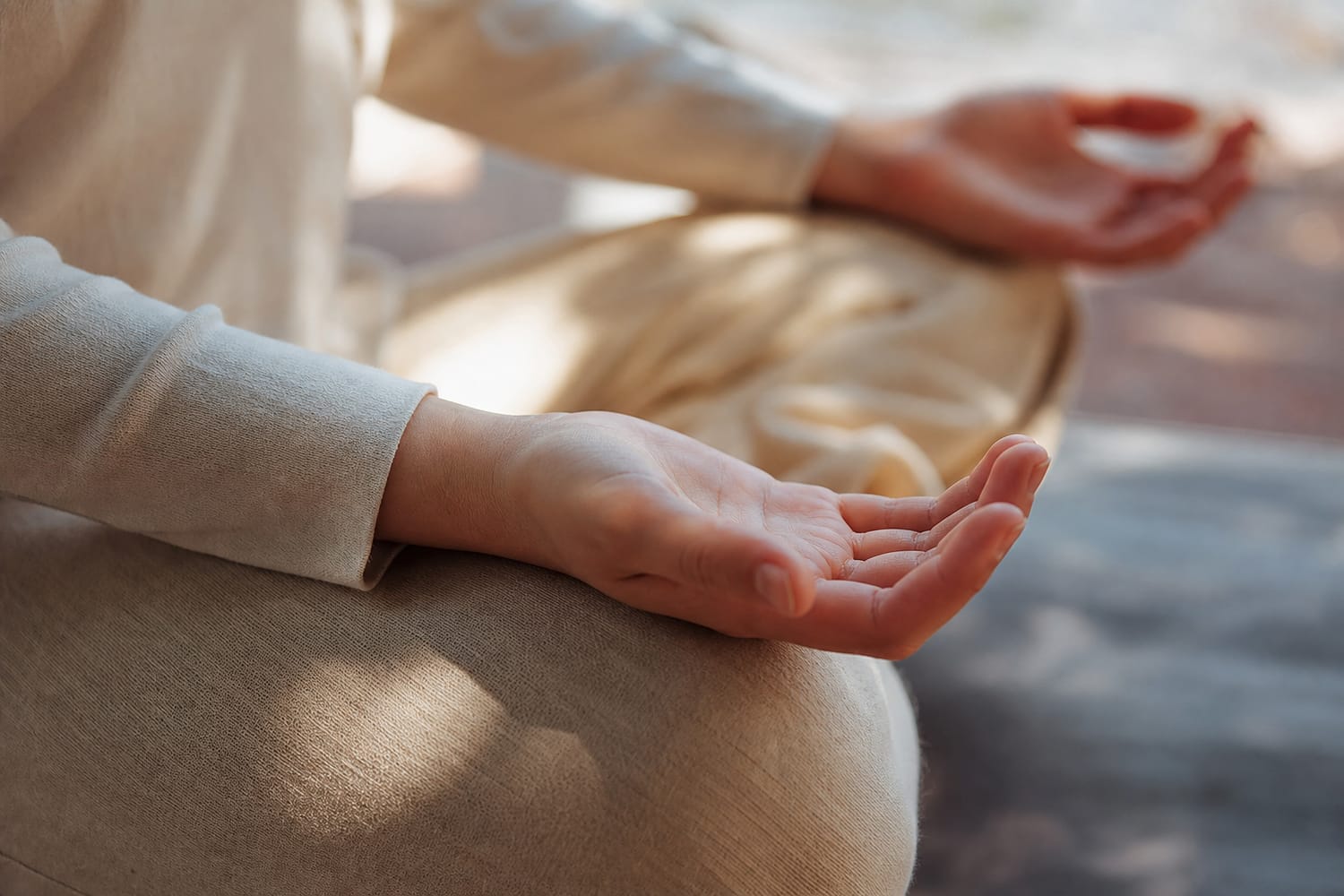 Hands resting palms up on the knees in a relaxed meditation pose, soft natural light.