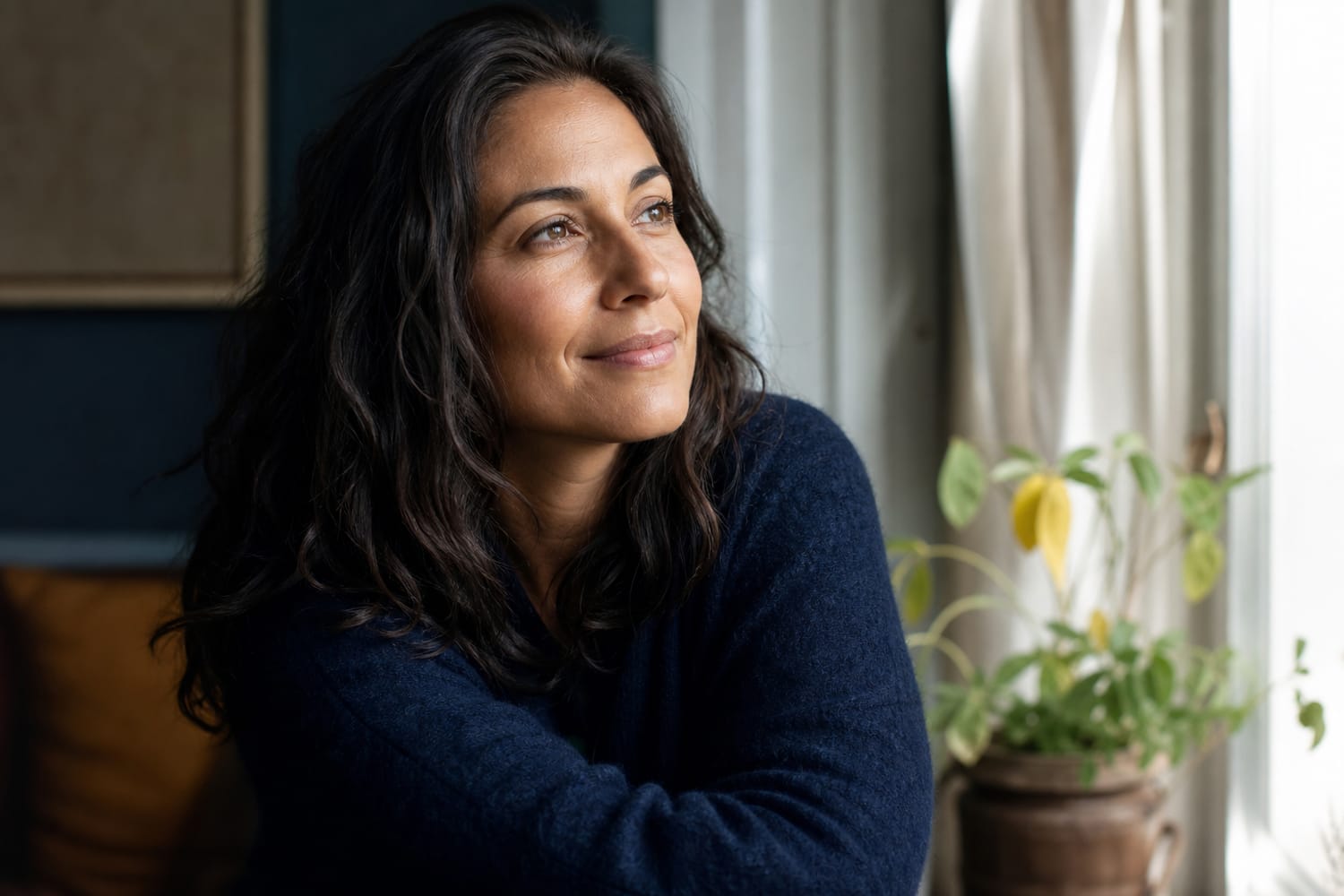 A woman with a calm, quietly confident expression in soft natural window light.