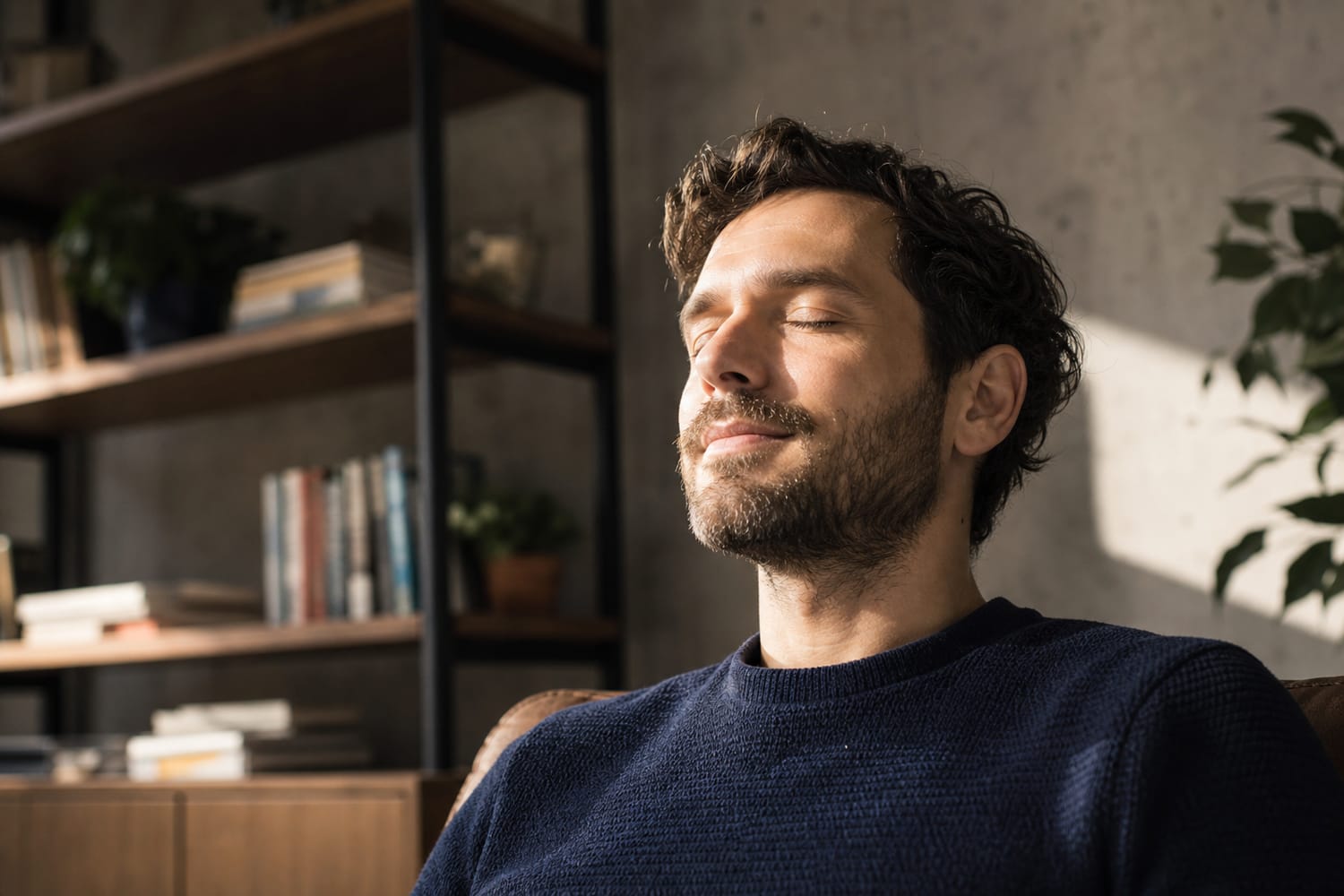 A man sitting with eyes closed and a faint hopeful smile, calmly visualising a goal.